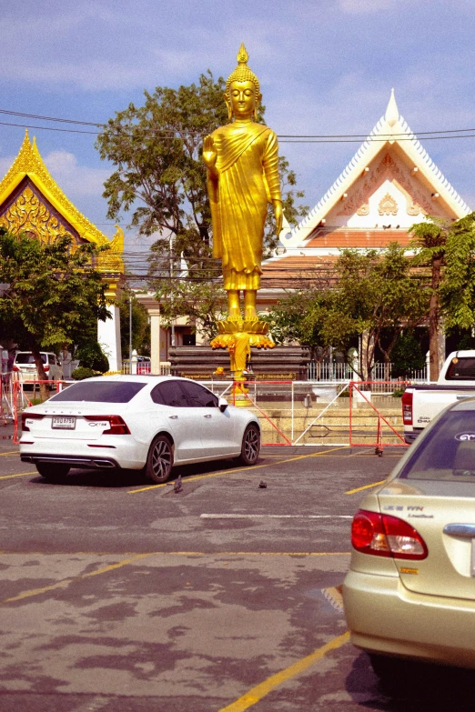 a gold statue on display next to a car