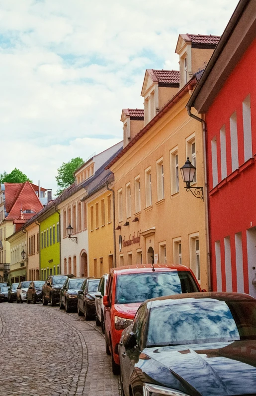 cars parked along a bricked street lined with houses