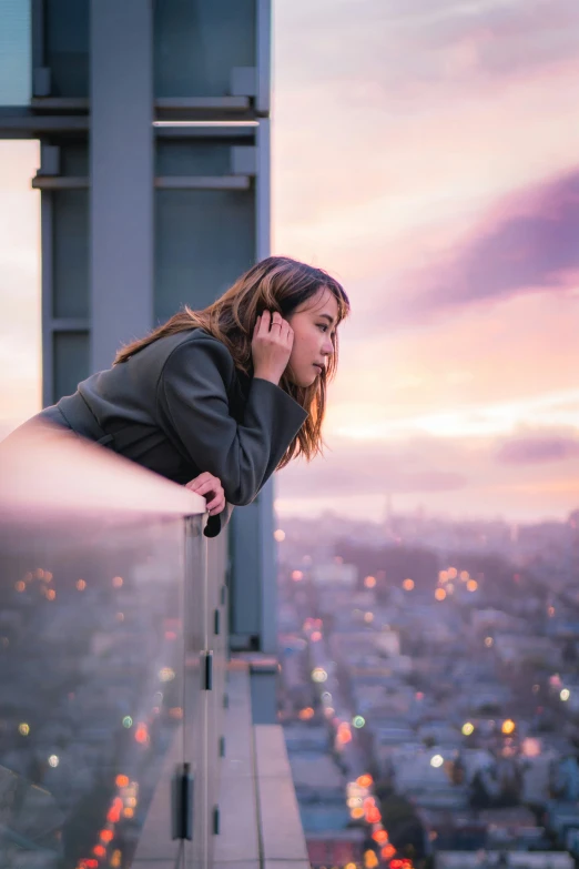 a woman talks on her cell phone while overlooking a city at night