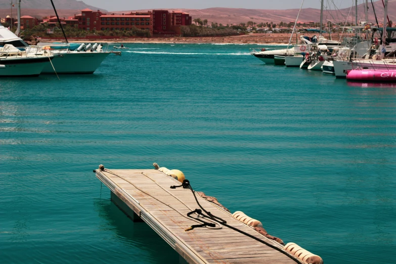 a pier near the shore surrounded by lots of small boats