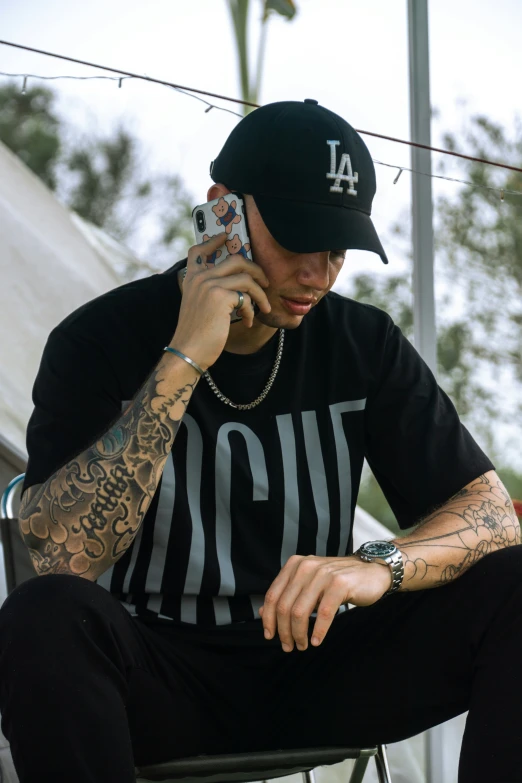 a man with tattoos sitting on a chair talking on his cell phone