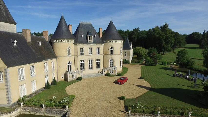 a red car parked in front of an old castle like home