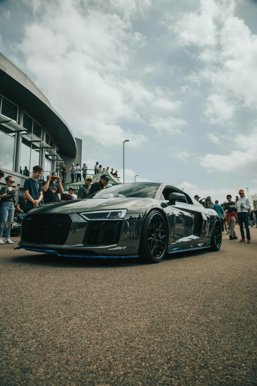 a gray sports car parked in front of people