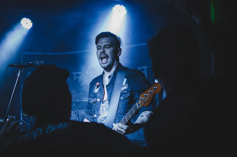 a man standing at a stage playing music on his guitar