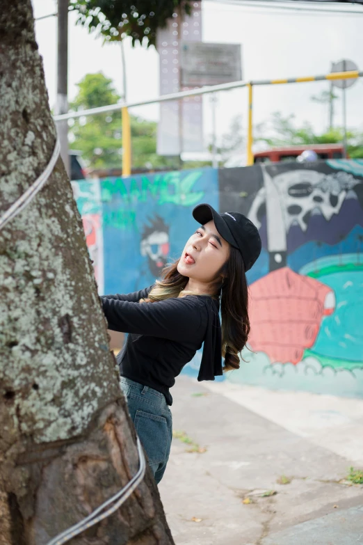 a  leans against a tree and poses