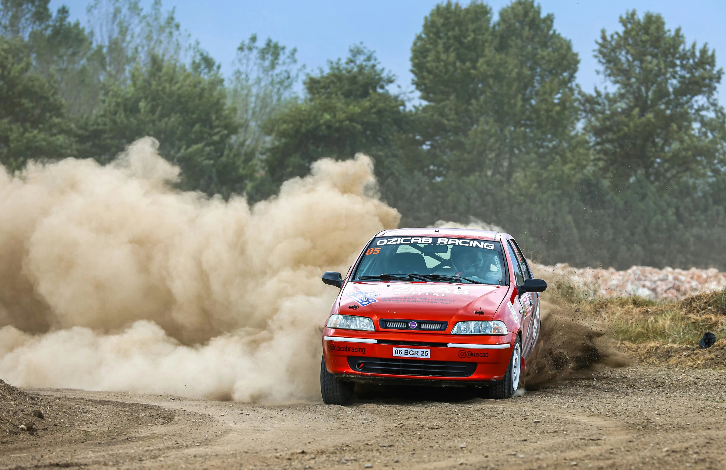 a red car going down the dirt road