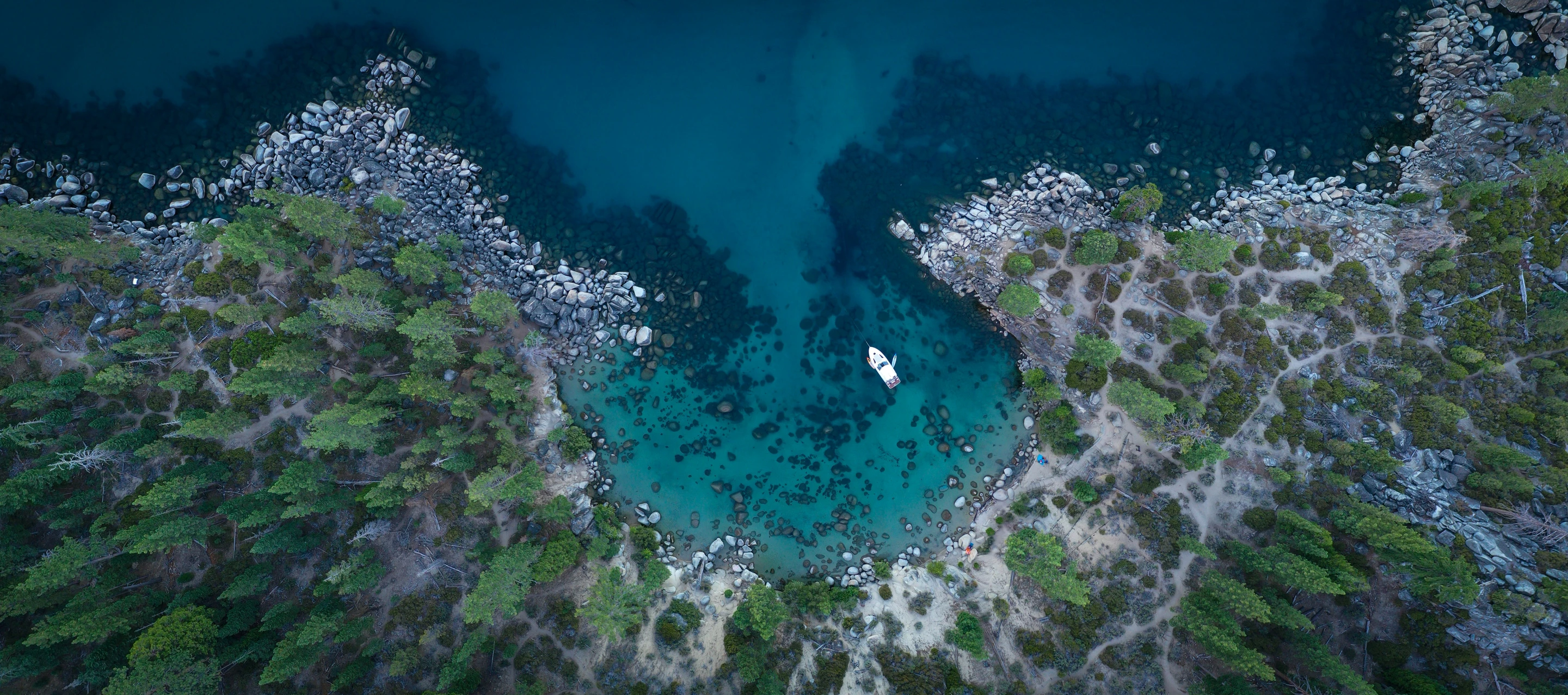 an aerial view of a lake surrounded by trees and rocks