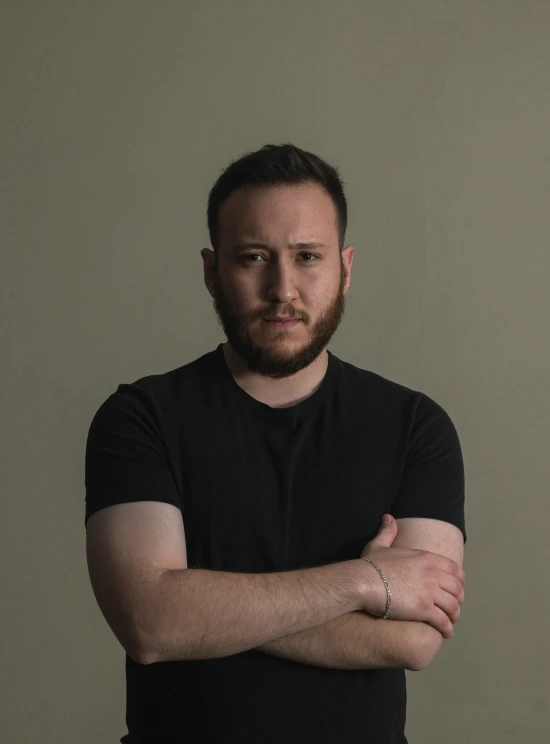 a man with his arms crossed posing for a picture