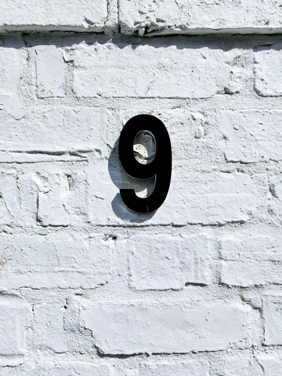 a number nine sign is on a white brick wall