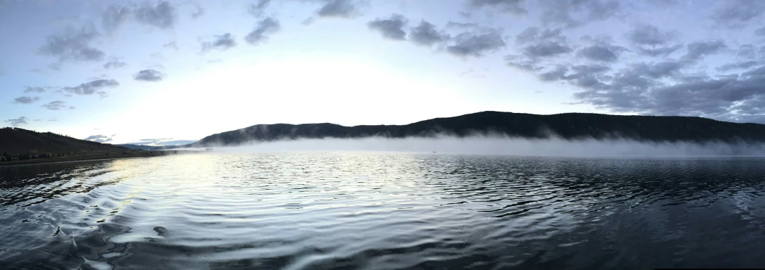 a foggy sky over a mountain lake