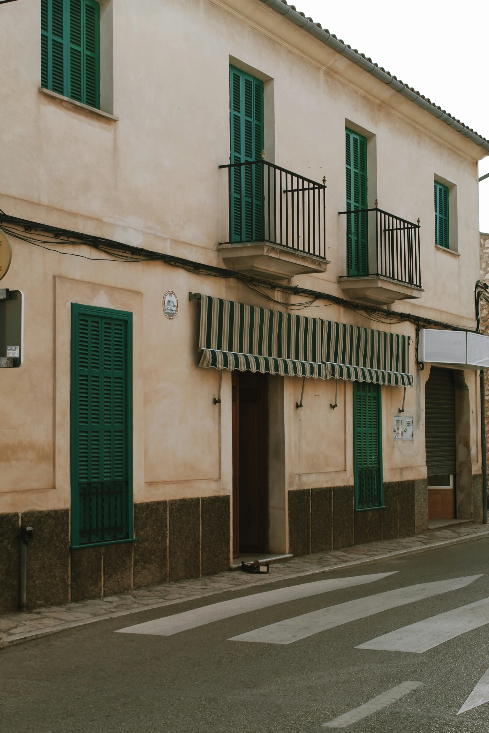 a building with green shutters next to street with stoplight