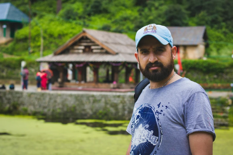 a man with beard standing in front of a lake