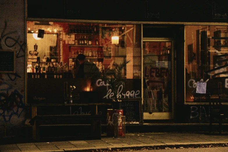 a dark night scene with a shopfront covered in graffiti