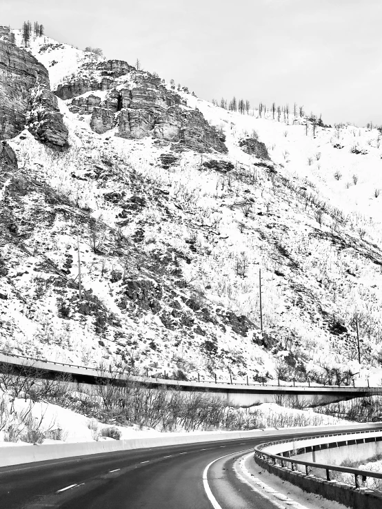 road surrounded by hills and snowy slope on side