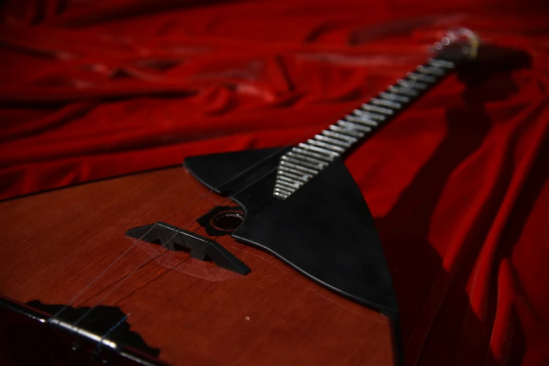 an acoustic guitar lying on a red sheet