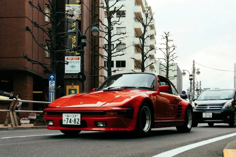 red sports car driving in the middle of a city street