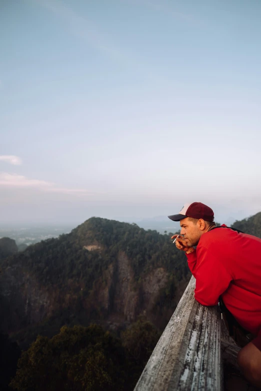 man on ledge of high cliff looking at mountain area