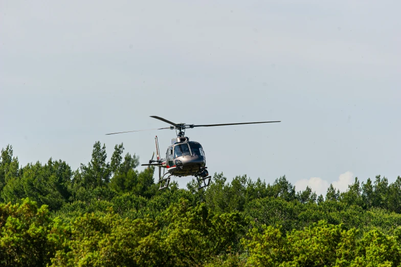 a helicopter flying low over some trees