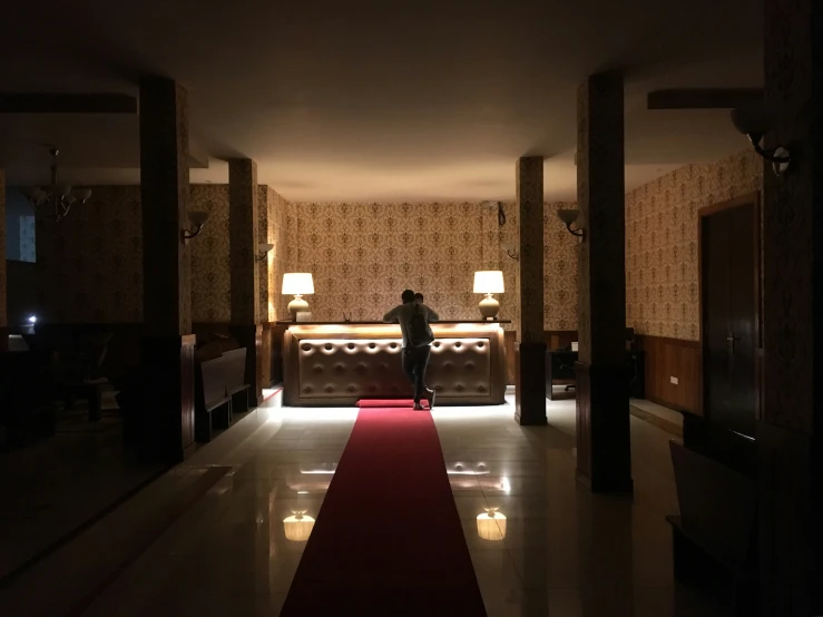 a man standing in front of a red carpet next to the lobby