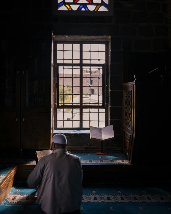 man sitting in the corner of an open window looking outside