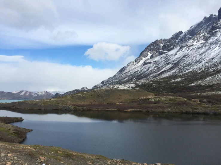 a snow covered mountain is shown next to a small lake