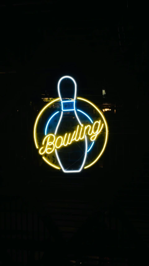 a sign for a bowling center lit up in the dark