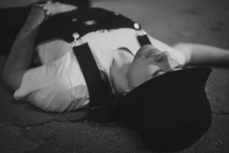 black and white image of boy in overalls laying on the ground