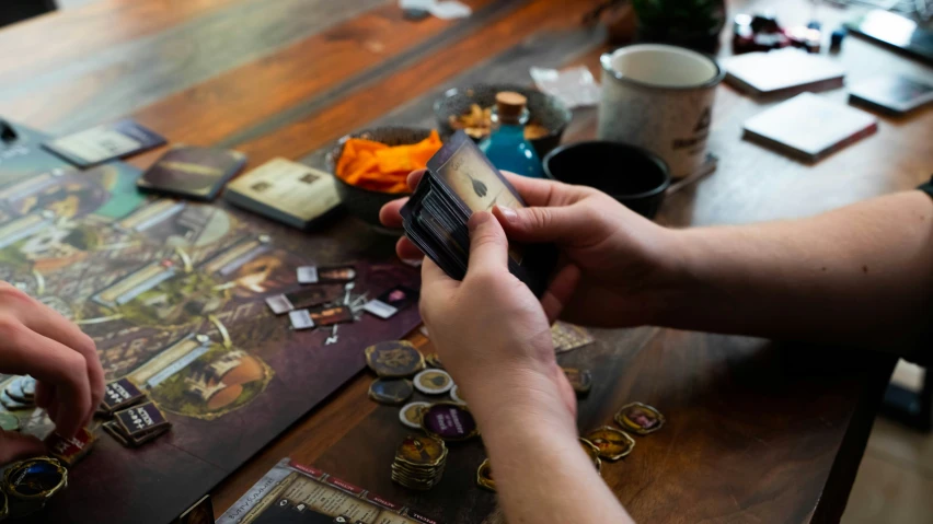 people playing with some cards and other items on a wooden table