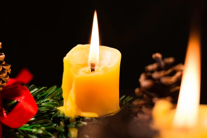 three candles are lit on a decorated pine tree