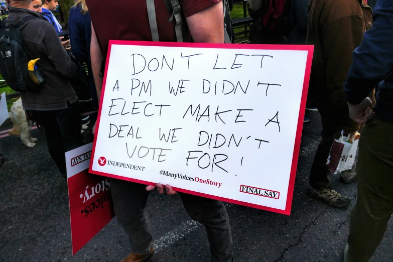a man wearing glasses holds up a sign with words
