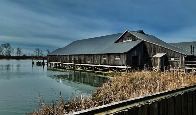 an old barn on the edge of a lake