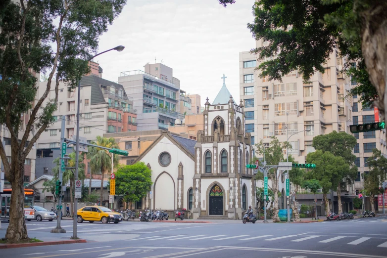 a building stands near the street light, and a yellow taxi passes by