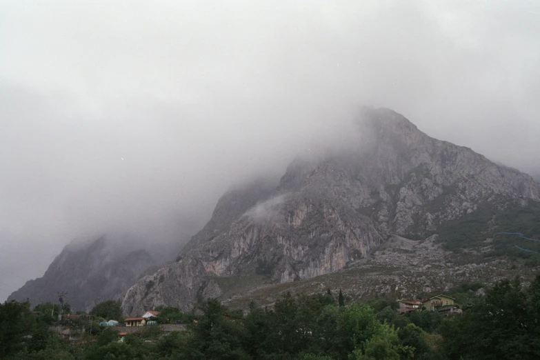 the mountain peaks in heavy fog above a forest