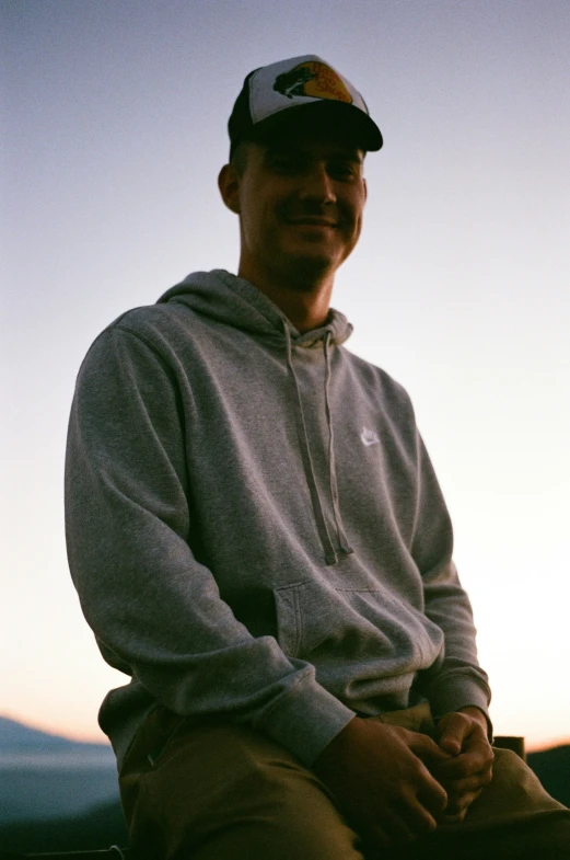 the man in a hat sits on a bench near mountains