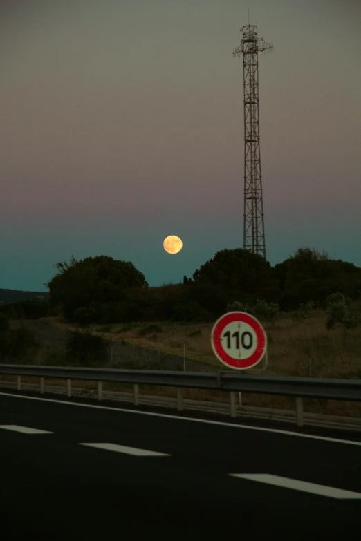 a full moon over an empty highway in the evening