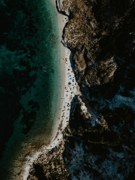 a long, stretch of beach near a cliff on a rocky shore