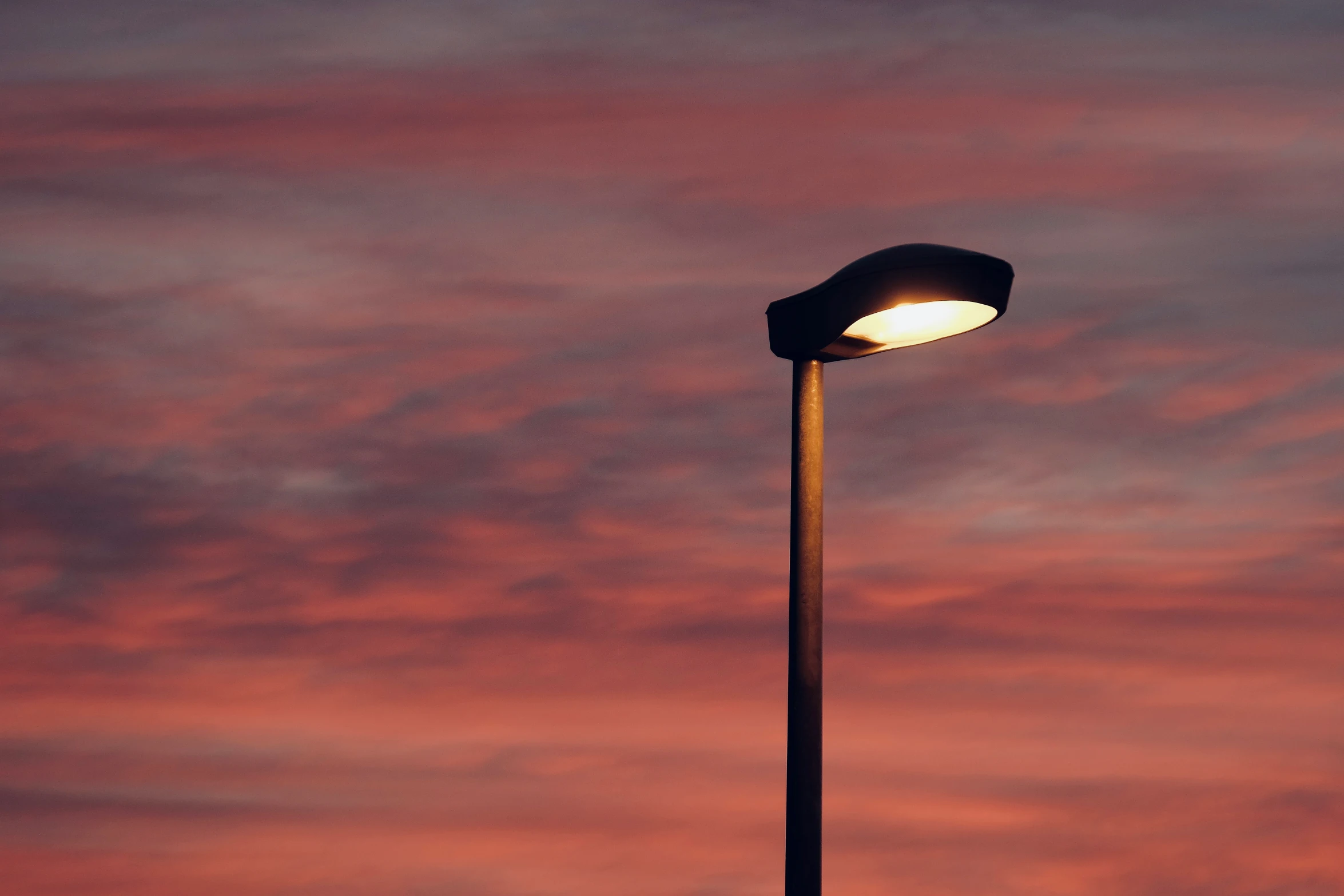 a street light against a bright pink and purple sky