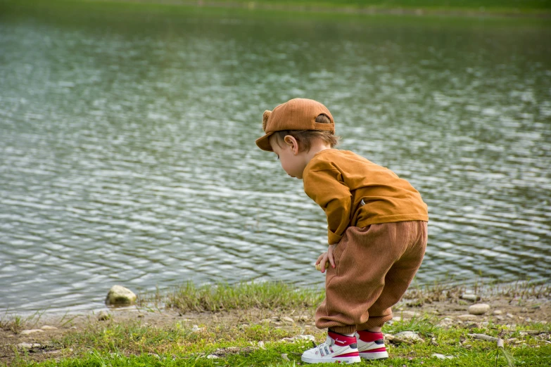 little boy standing on a rock at a lake looking at soing