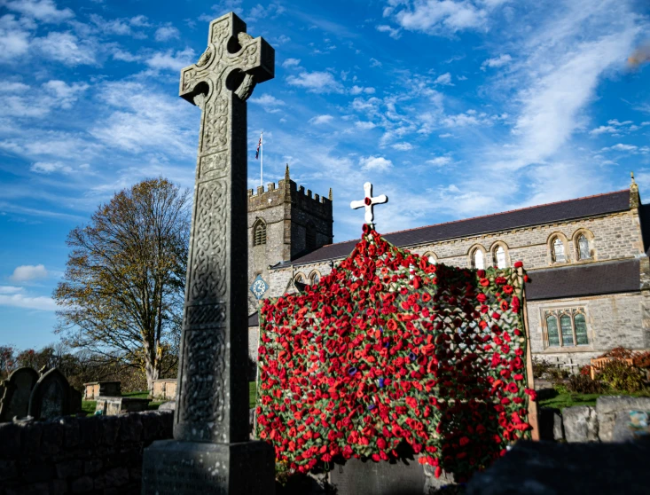 there is a stone cross in the yard with poppies covering it