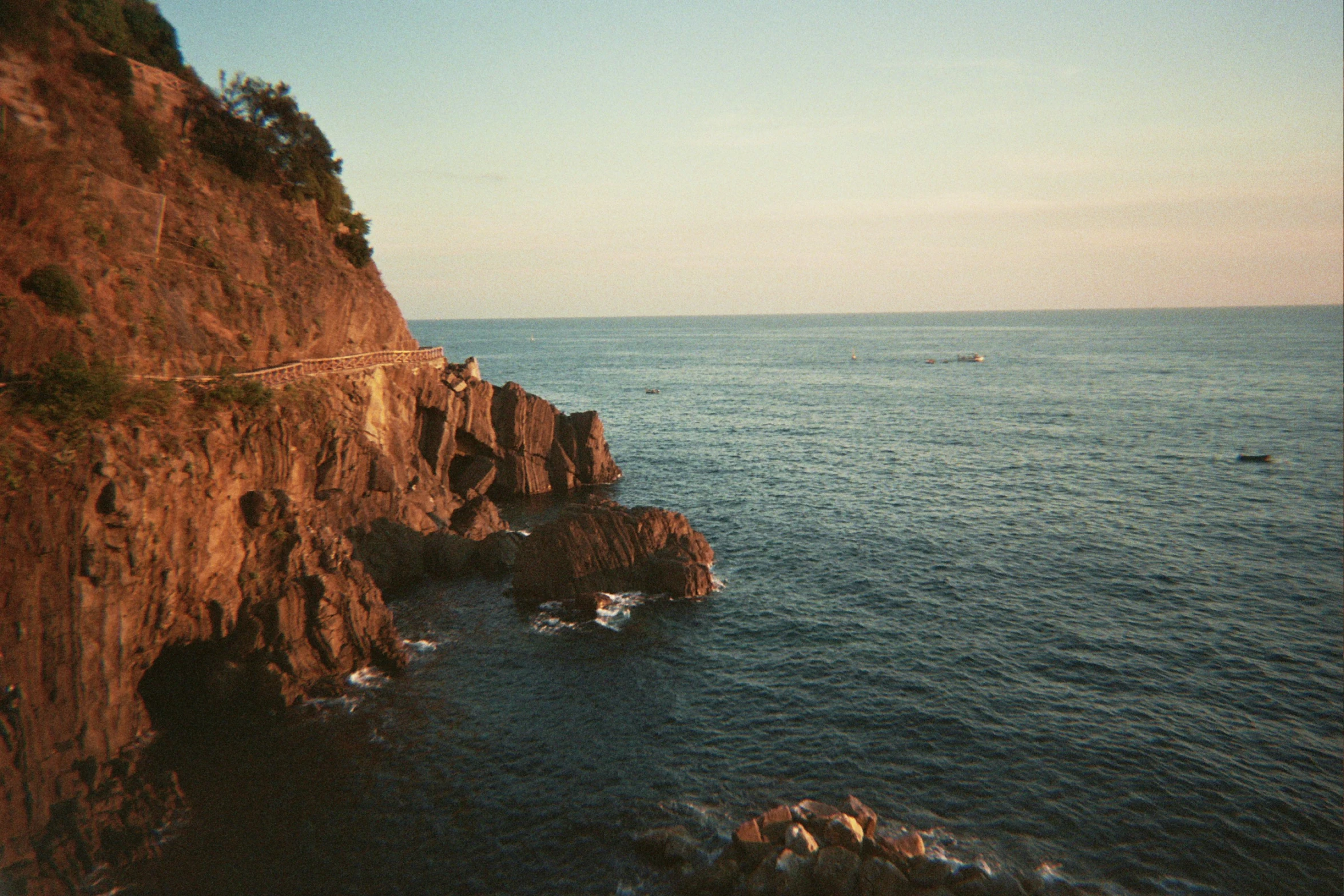 a couple of small boats on the water off of a cliff