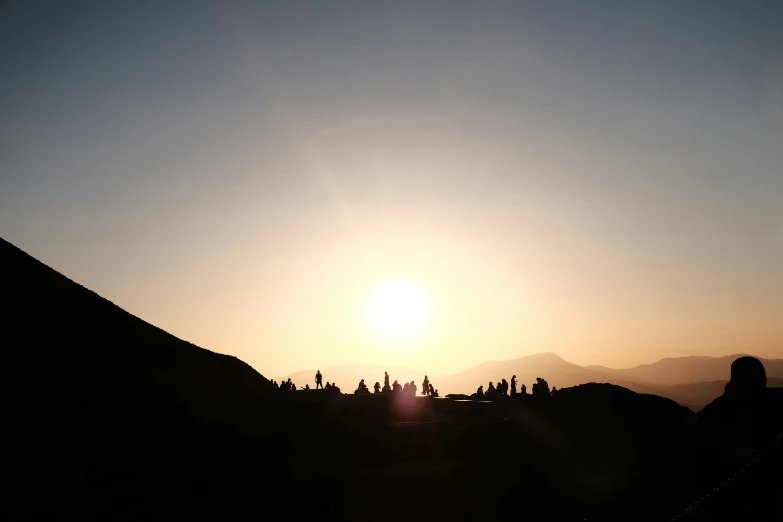 a man standing next to a large hill at sunset