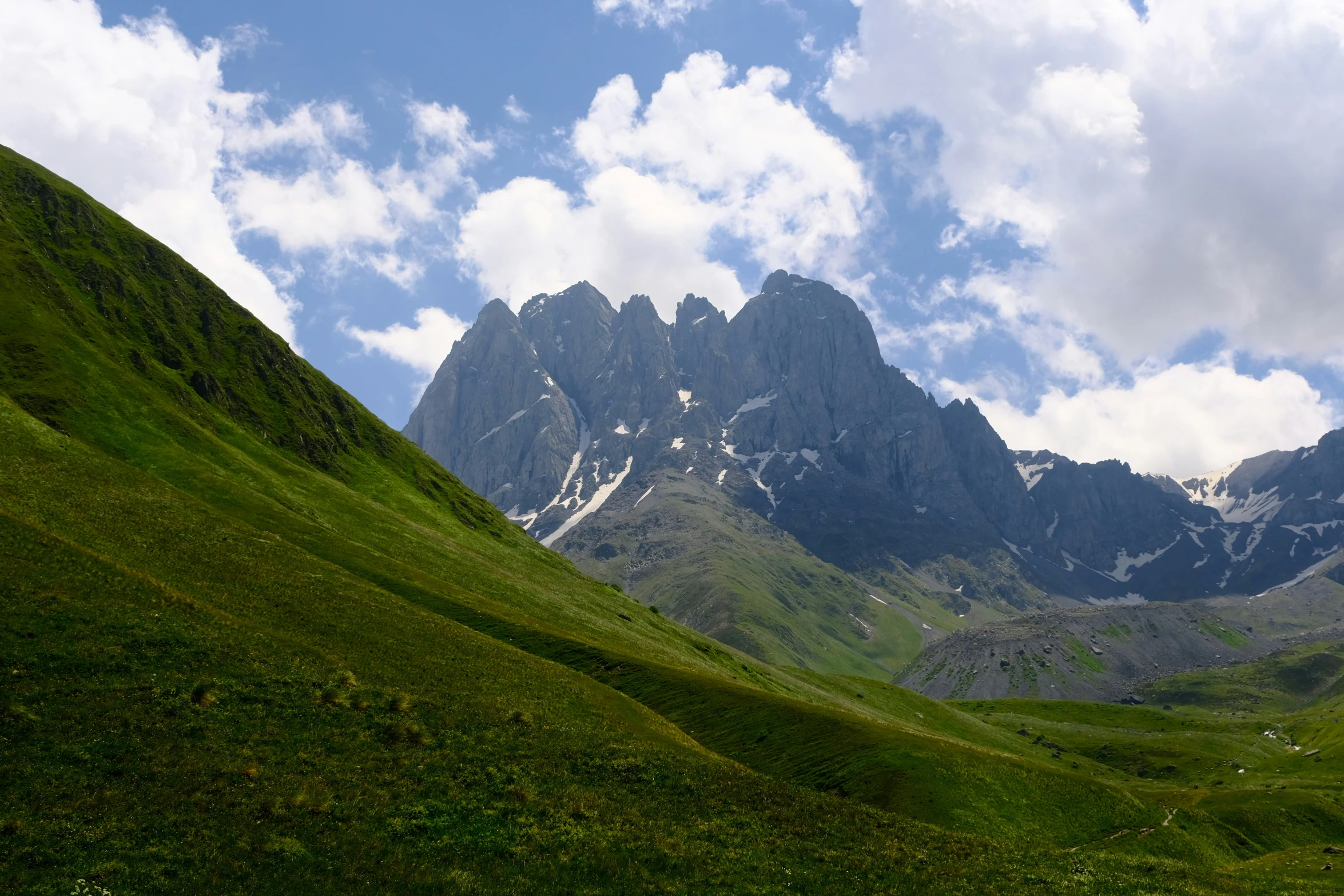 the mountains are covered in clouds and green grass