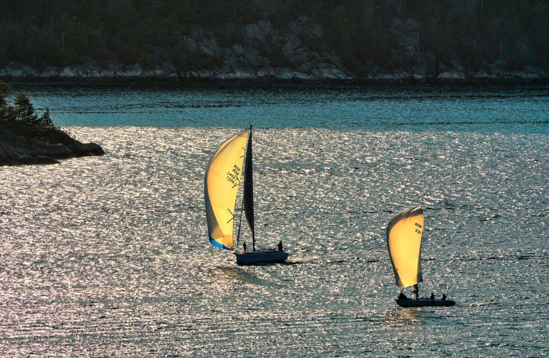 two sailboats floating on the water at sunset