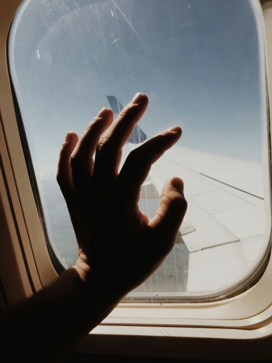 person's hand out of an airplane window
