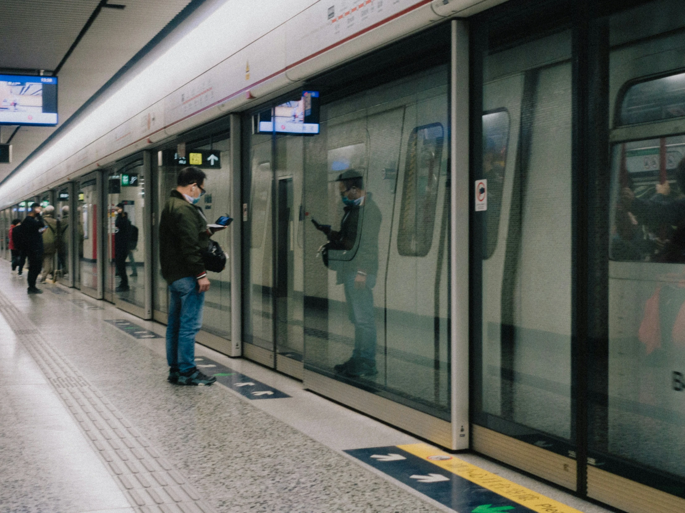 there is a man looking at his cellphone outside a train