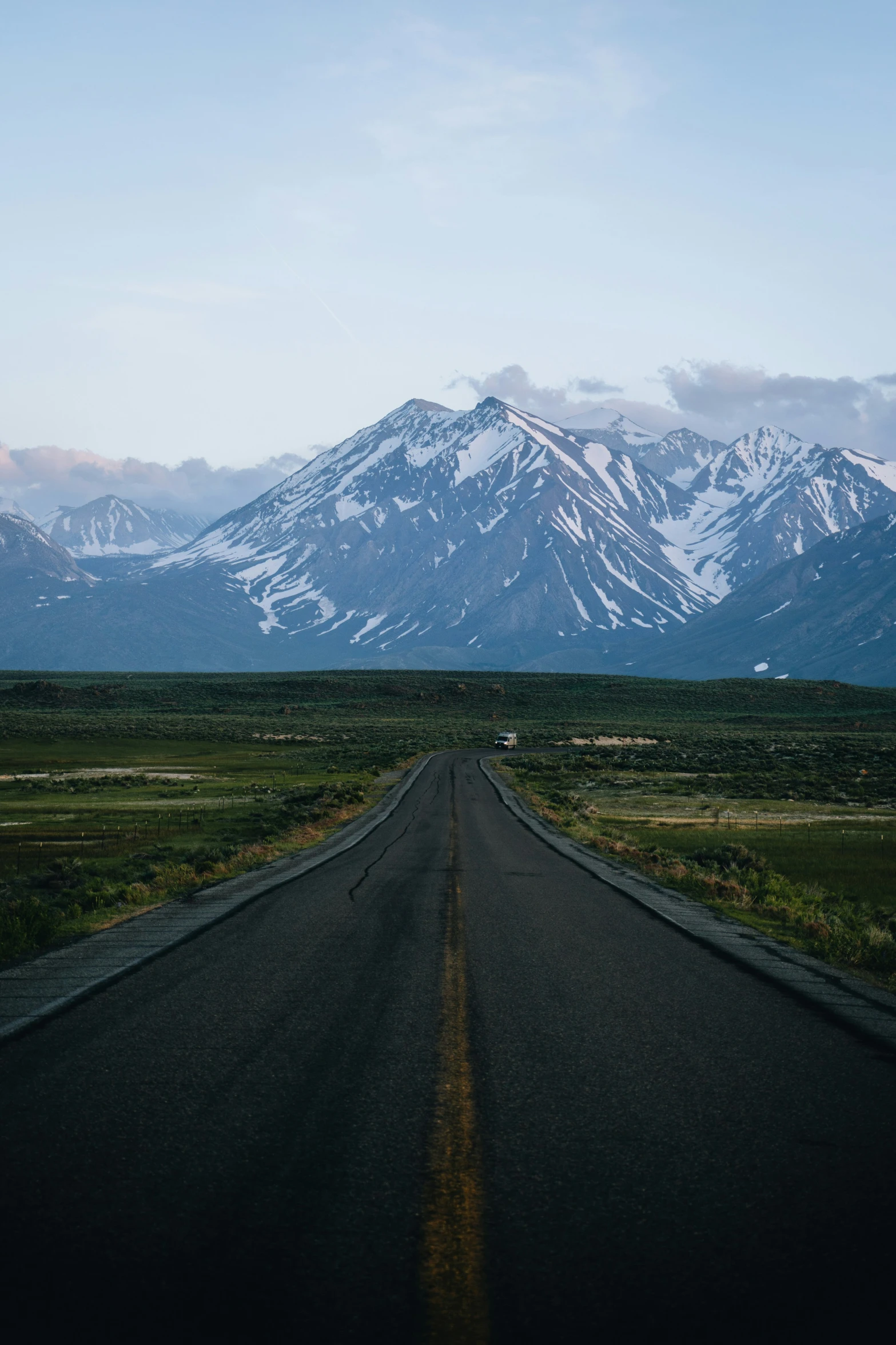 a deserted road with snow - capped mountains on the side