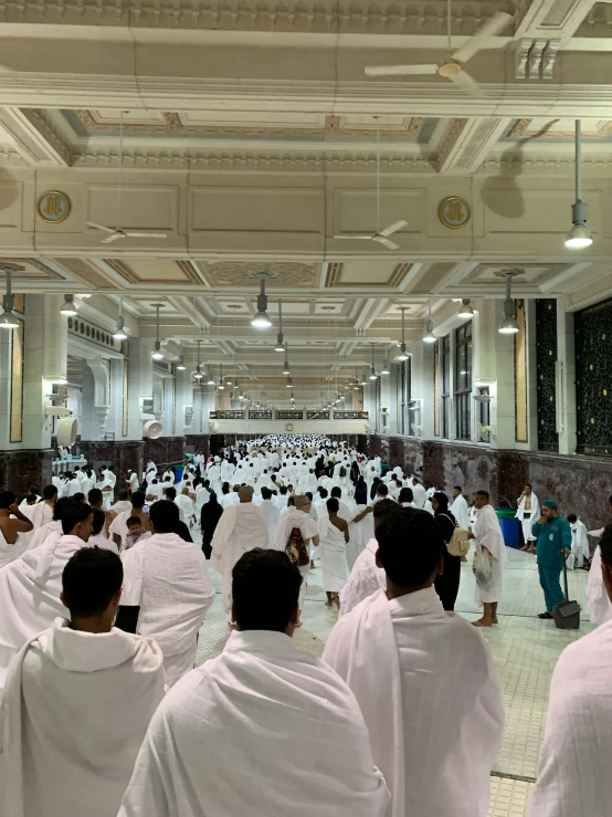 a group of people in white robes are standing in a hall