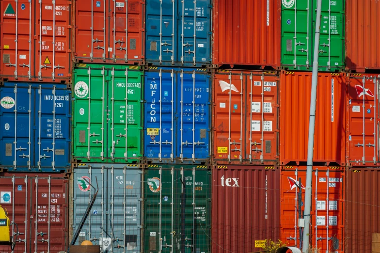 several shipping containers stacked side by side, each with different colored containers