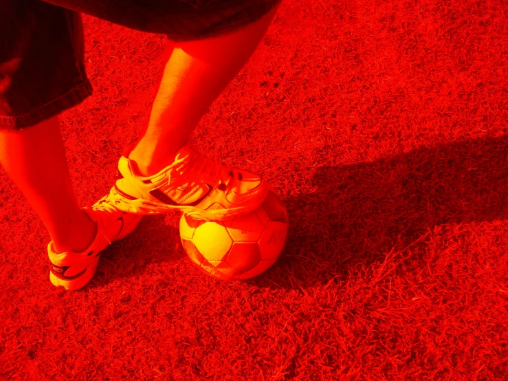 a soccer ball in the shadow of a person's feet
