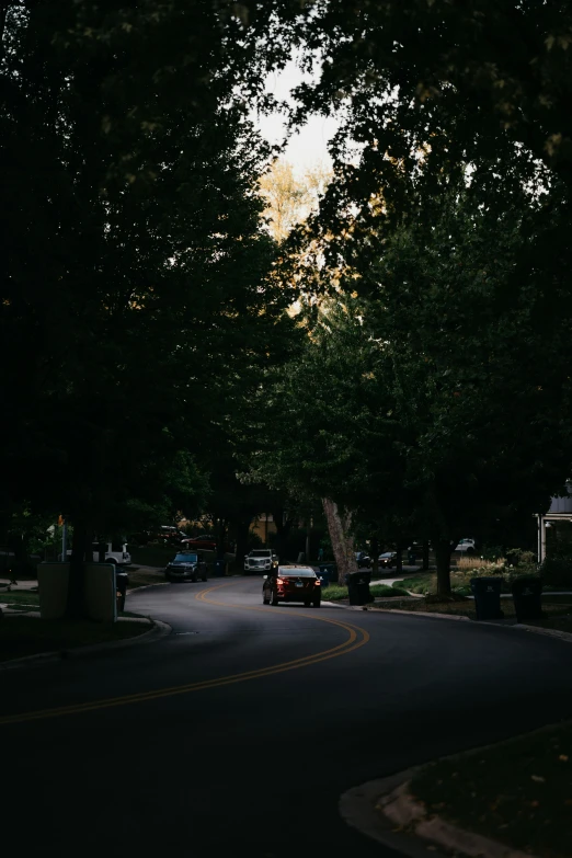 a car driving down a city street under trees